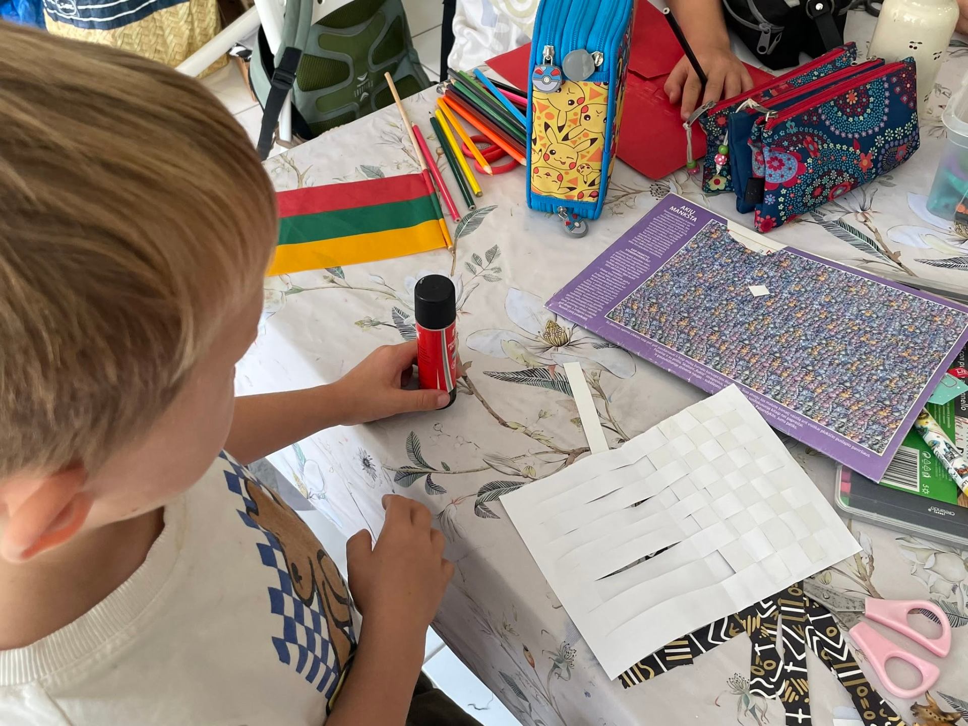 Child crafting with the Lithuanian flag on the table